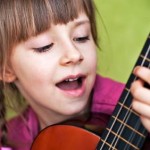 Mädchen mit Kindergitarre singt